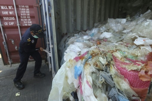 Un policier indonésien ouvre un conteneur rempli de déchets illégalement importé vers le pays, à Batam le 29 juillet 2019 © AFP SEI RATIFA