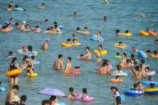 Des baigneurs pataugent dans les vagues à Qingdao, l'une des stations balnéaires les plus réputées de la côte chinoise, le 21 juillet 2019 © AFP STR