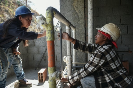 femmes qui travaillent sur la plomberie dans le bâtiment qu'elles construisent à Caracas