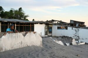 homme maison détruite par la montée du niveau de la mer, sur la plage de Cedeño, Honduras