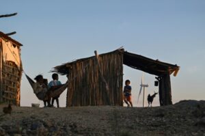 Des enfants de la communauté indigène Wayuu jouent dans leur maison à côté d'un parc éolien