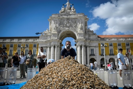 Un militant pour la protection de l'environnement pose devant un tas de mégots de cigarettes entassés sur une place