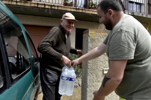 Un employé municipal livre des packs d'eau à un habitant
